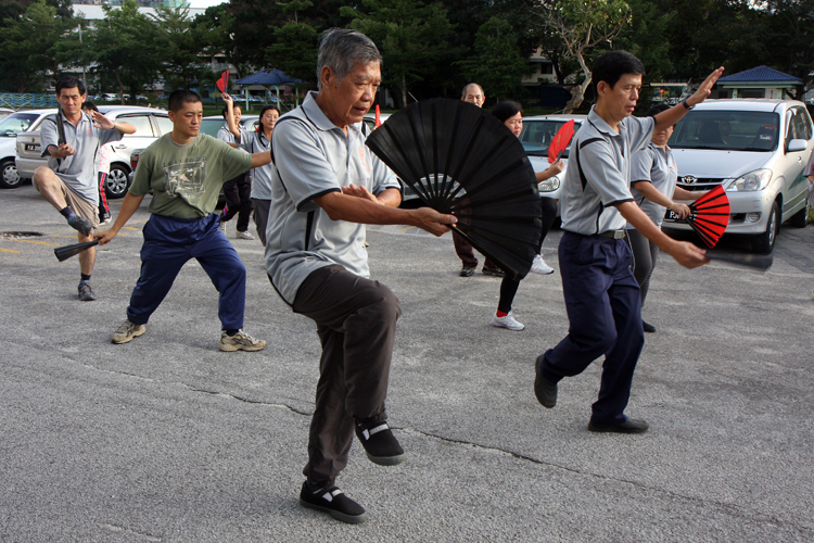 邓敬荣教练为进阶学员示范太极功夫扇的一个撩扇动作 —— ‘金鸡独立’