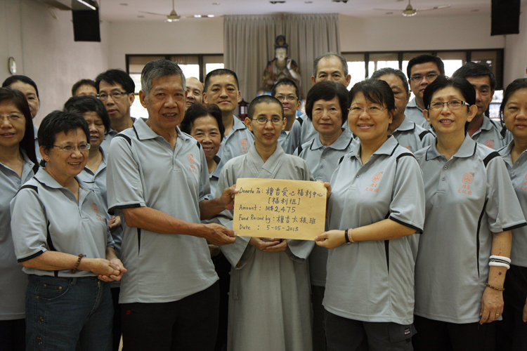 邓敬荣教练移交学员乐捐之善款于檀香爱心福利中心属下福利组义务秘书郑盈娟居士,由真醍法师见证