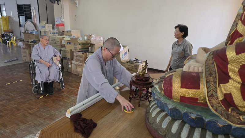 在第三楼层,法师们和义工们齐心协力清理佛像。